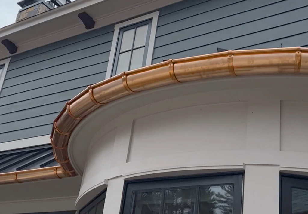Copper gutters on a house exterior with gray siding.